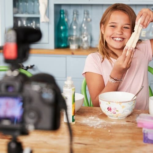 Young girl video blogging in kitchen