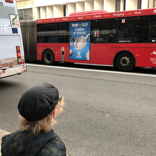 Child looking at red bus with Krispy Kreme ad