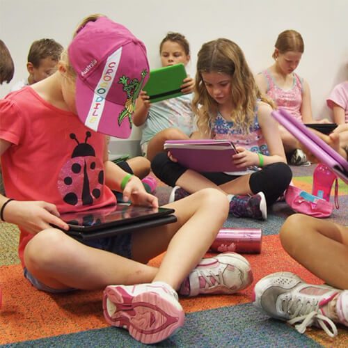 Groups of children seated looking at ipads