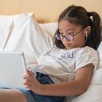 Asian girl wearing glasses using an iPad