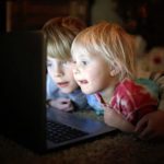 Two children staring into a laptop screen