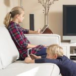 Two children at home on the lounge using tablets.